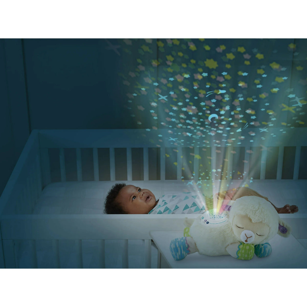 Baby in a crib watching stars projected on the ceiling by the plush lamb