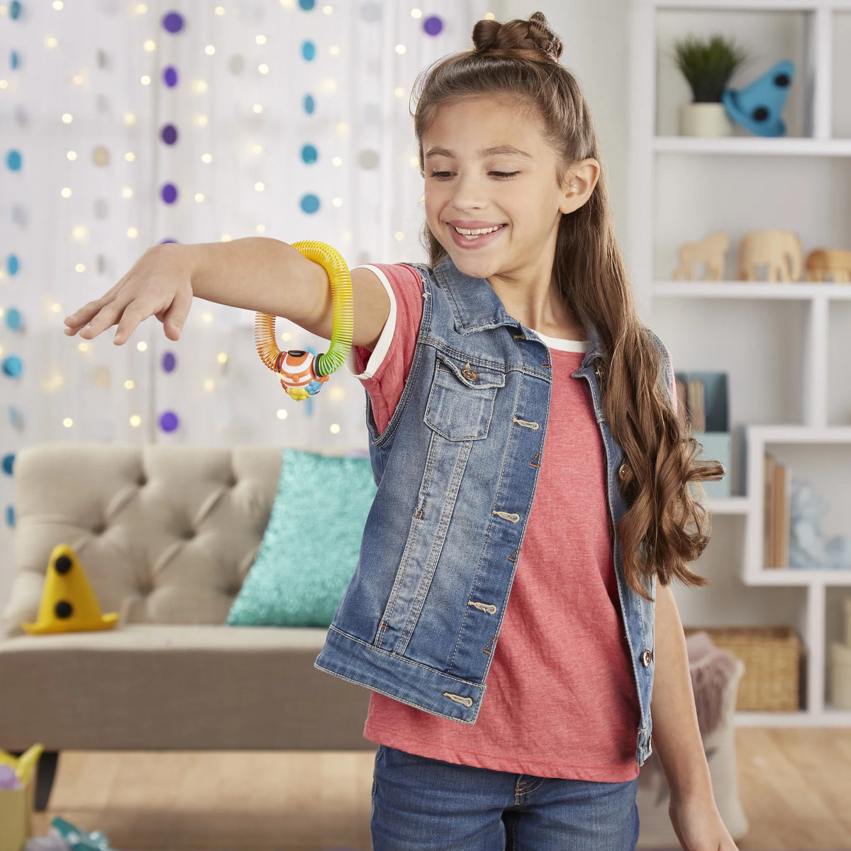 Girl in a denim vest with the rainbow spring toy coiled around her arm
