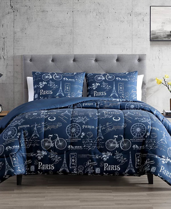 Navy comforter and shams printed with white Paris landmarks, bicycles and script on a gray bed
