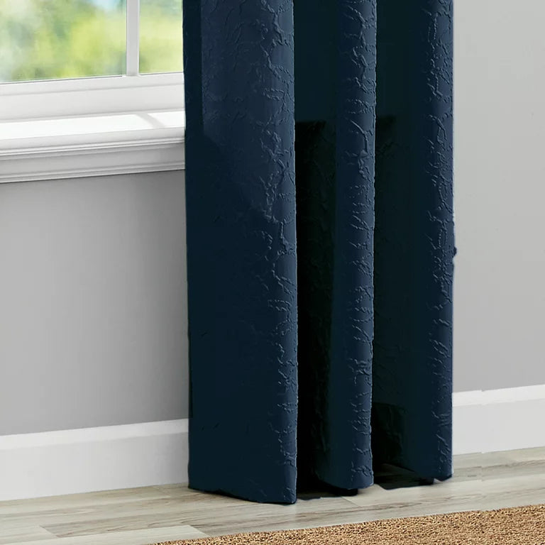 Hem of the navy curtain panels falling to the floor beside a window