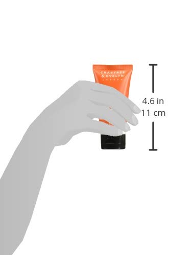 Hand holding the small orange body wash tube, about 4.6 inches tall