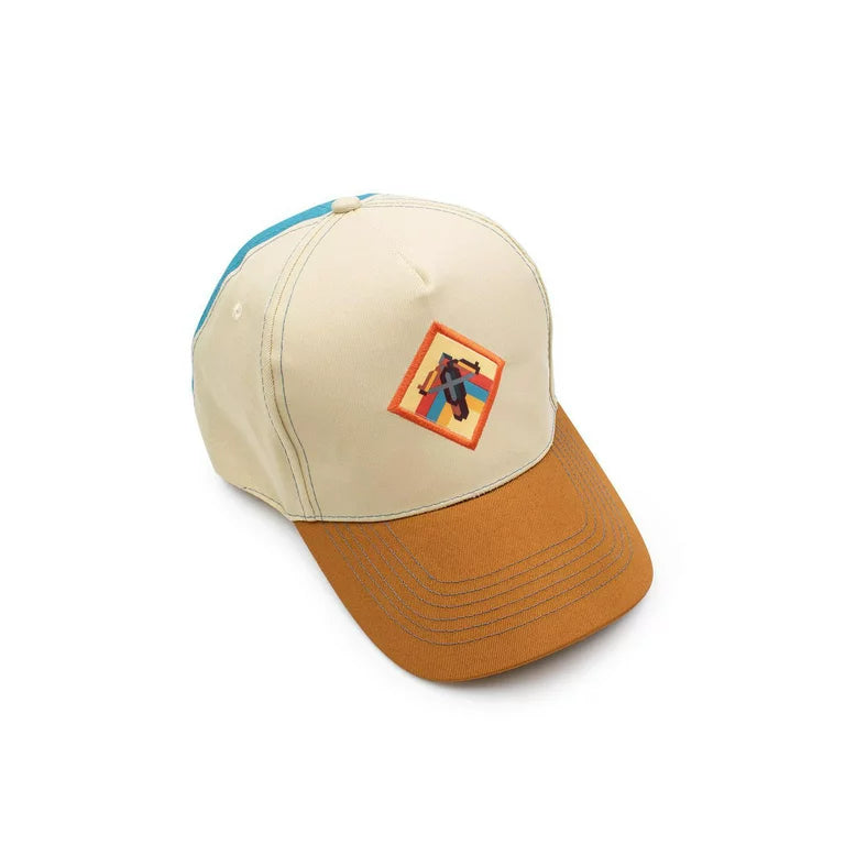Cream and tan snapback cap with a crossbow patch and teal back panel