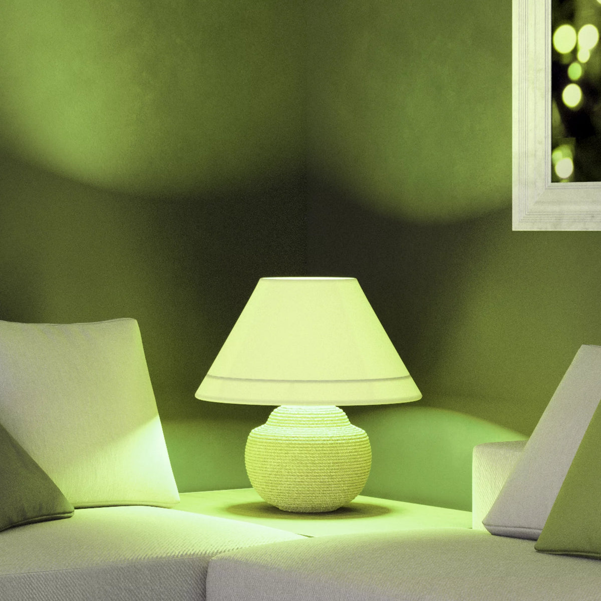 Table lamp glowing green beside a white sofa