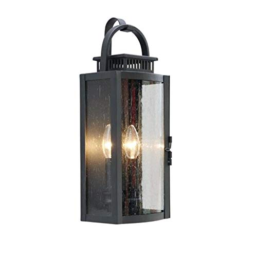 Black outdoor lantern wall light lit with two candelabra bulbs behind seeded glass