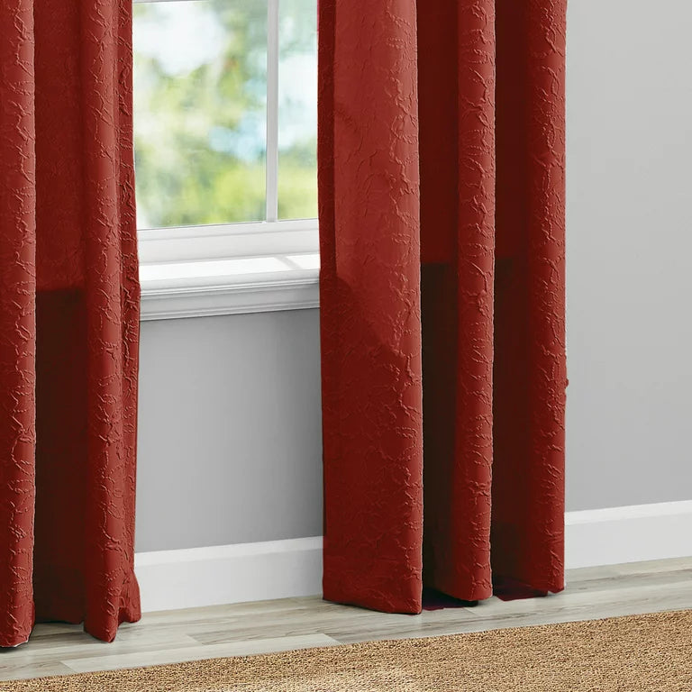 Hem of the rust red curtain panels on a wood floor beside a window