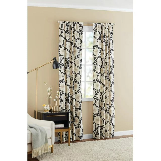 Black and cream floral panels on a window beside a brass floor lamp