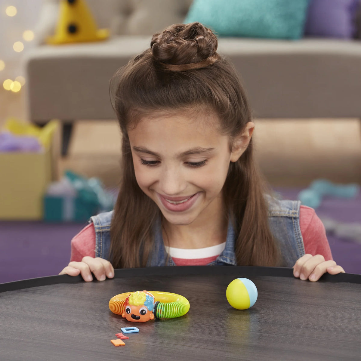 Girl with a braided bun smiling down at the clownfish spring toy on a table