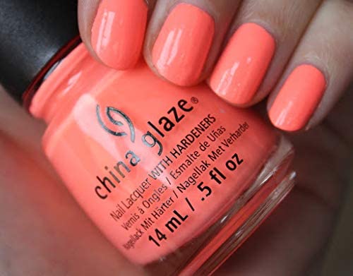 Close-up of neon coral nails gripping the coral polish bottle