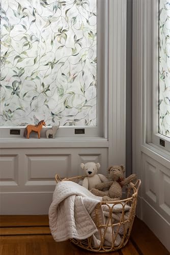 Nursery window with leaf-pattern privacy film above a basket of soft toys