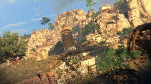 Gameplay scene of rocky cliffs with a stone tower and wooden walkways