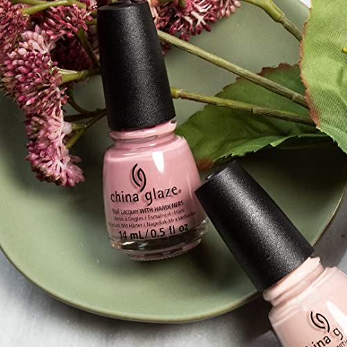 Pale pink polish bottles on a green plate with dried pink flowers