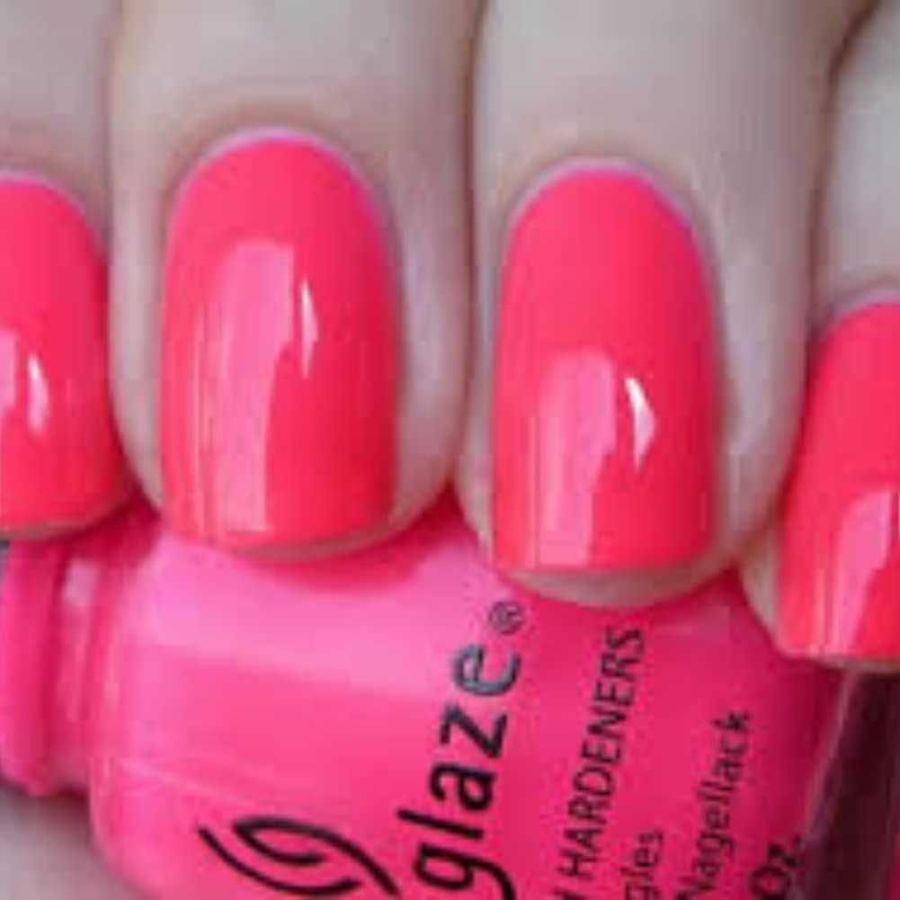 Close-up of nails painted neon coral pink above the bottle