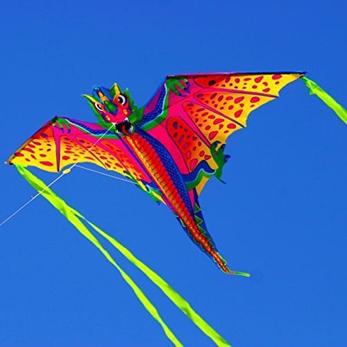 Pink, orange and yellow dragon kite with green tails flying in a blue sky