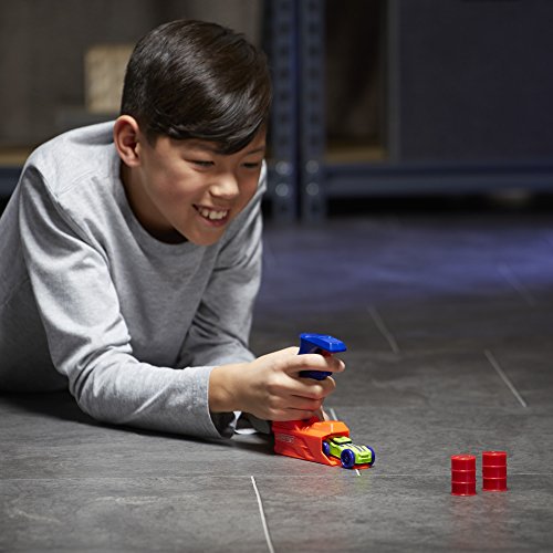 Boy lying on the floor aiming the loaded launcher at two red barrels