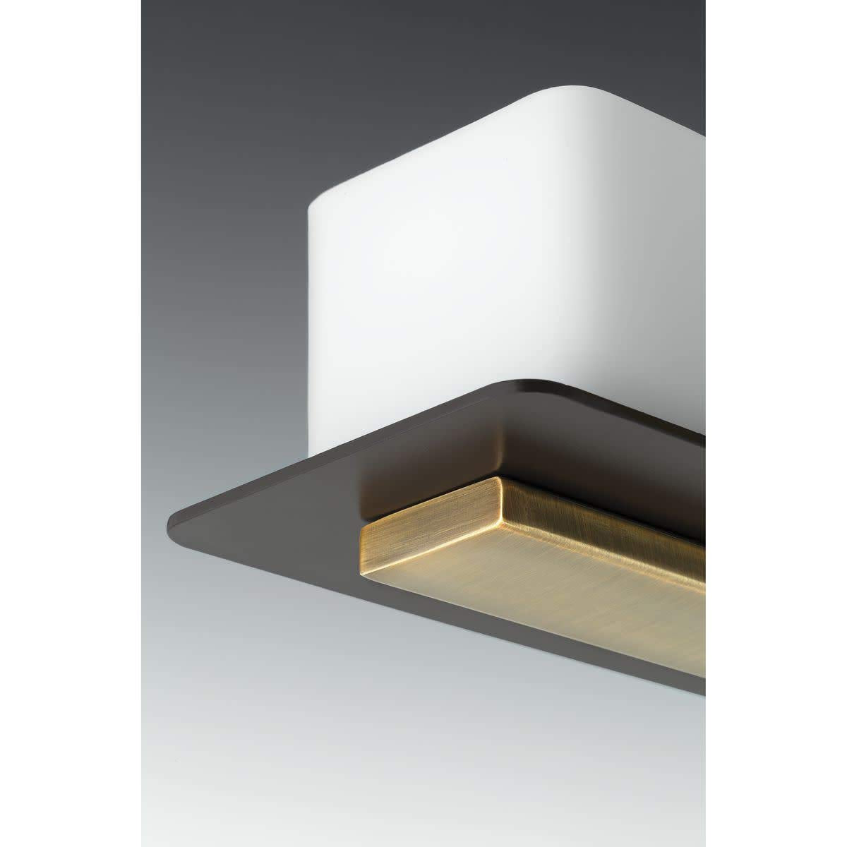 Close-up of a white shade resting on the bronze plate with a brushed brass block