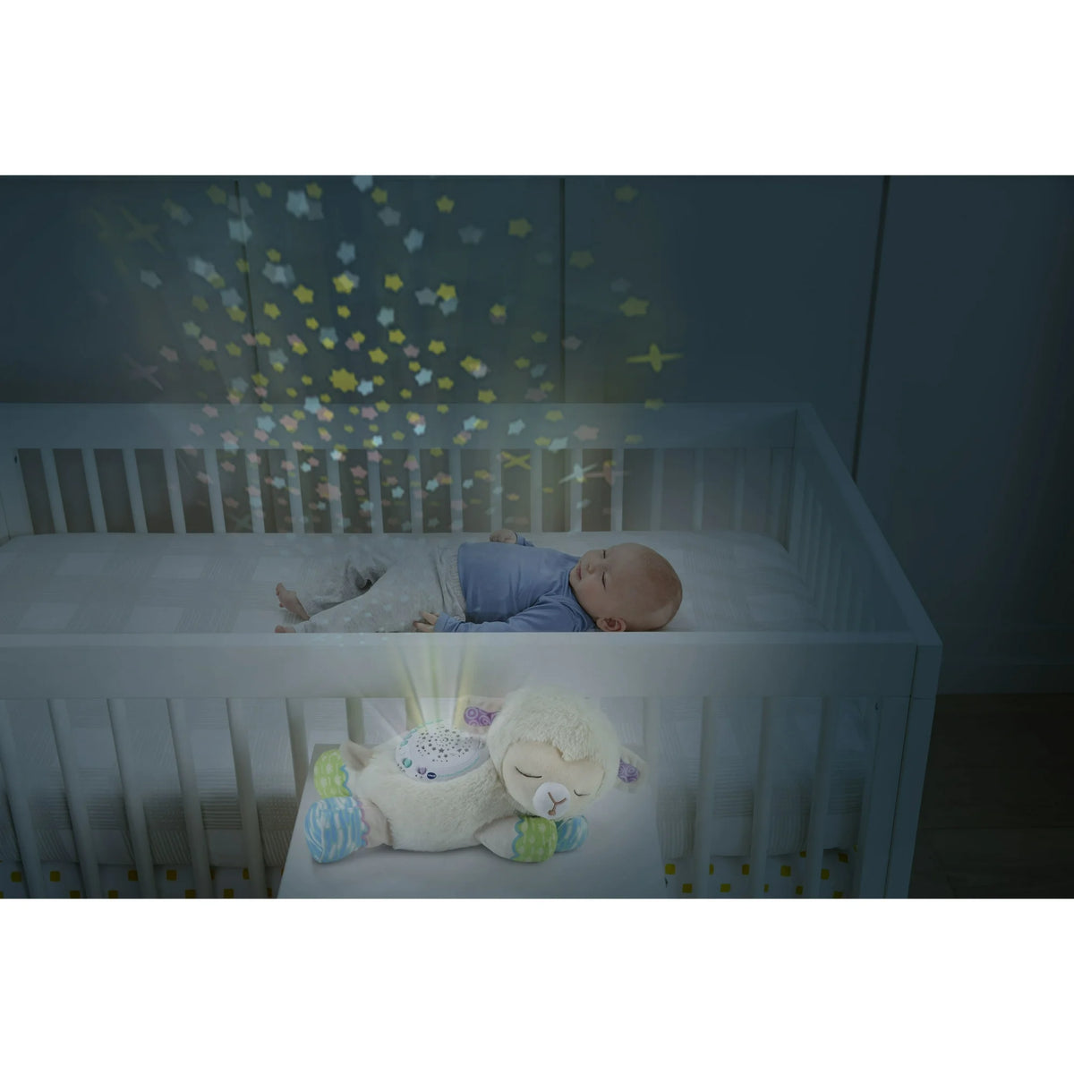 Sleeping baby in a crib under stars projected by the plush lamb