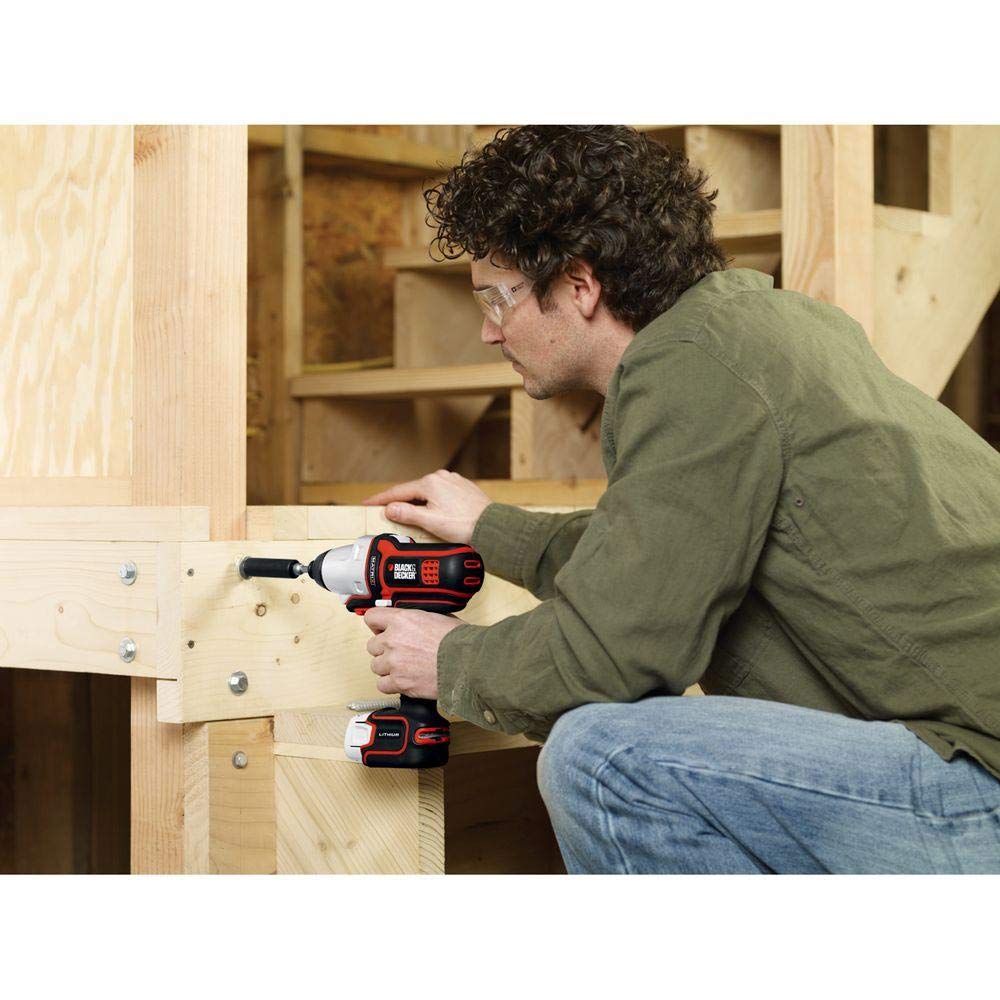 Man in safety glasses driving a lag bolt into a wooden stair frame with the impact tool