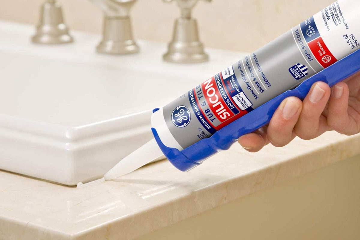 Close-up of a white silicone bead laid where a white basin meets a marble counter