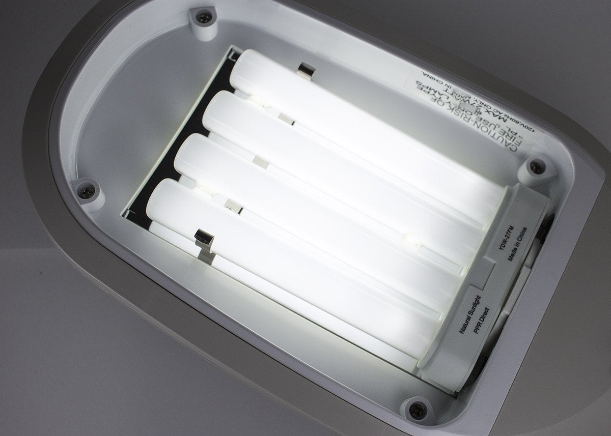 Lit four-tube fluorescent bulb fitted in a white lamp housing seen from above