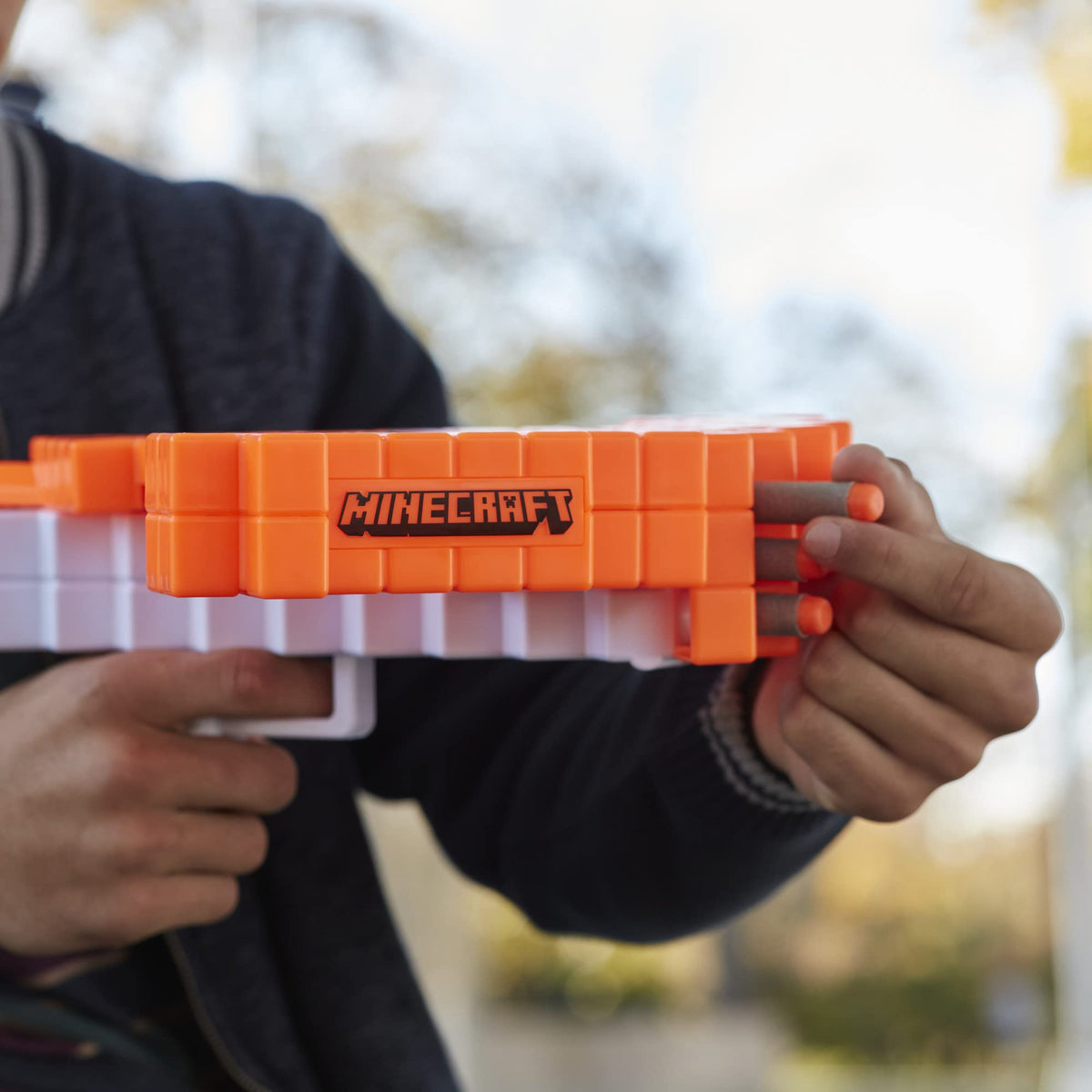 Hands loading foam darts into the front of the orange blocky crossbow
