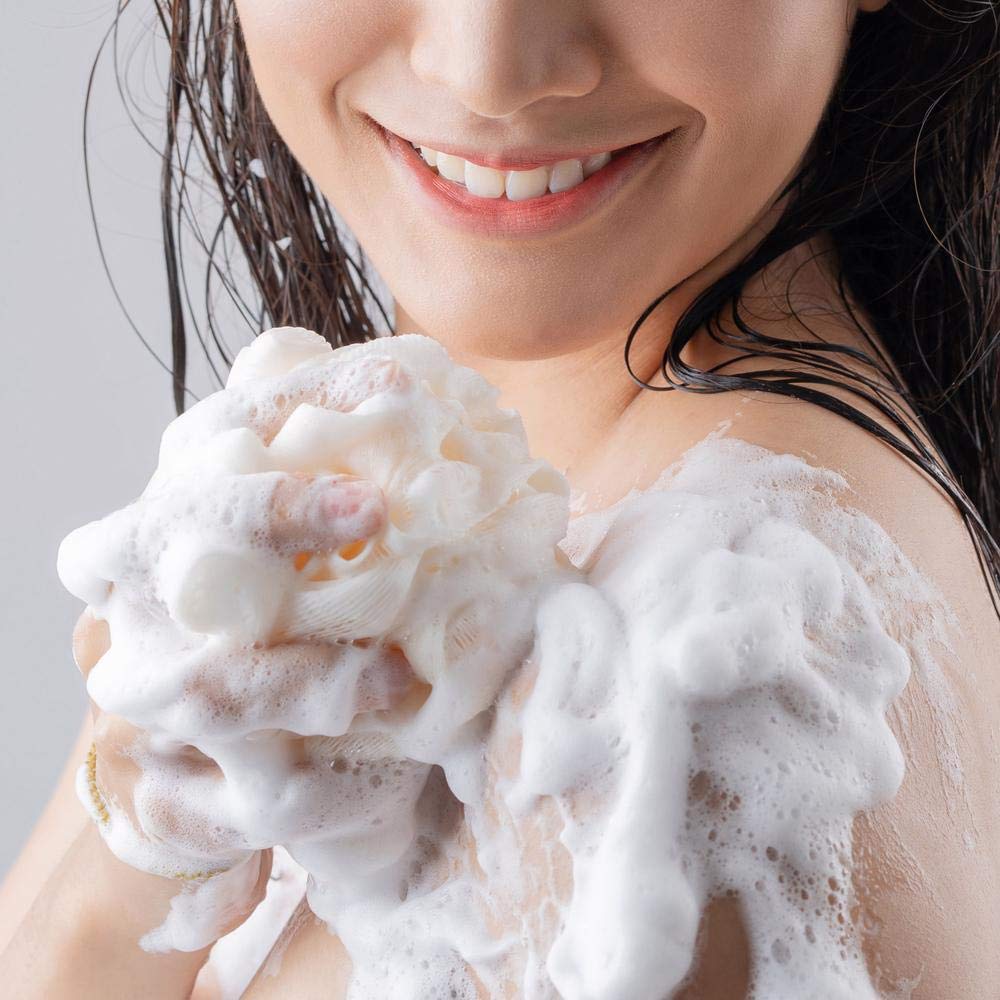 Smiling woman lathering her shoulder with a white bath puff