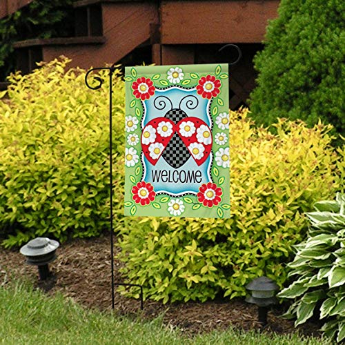 Ladybug Welcome flag on a stand in front of yellow shrubs
