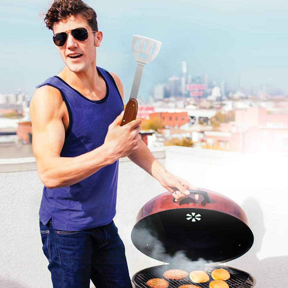 Man in sunglasses holding the wood-handled spatula over burgers on a rooftop kettle grill