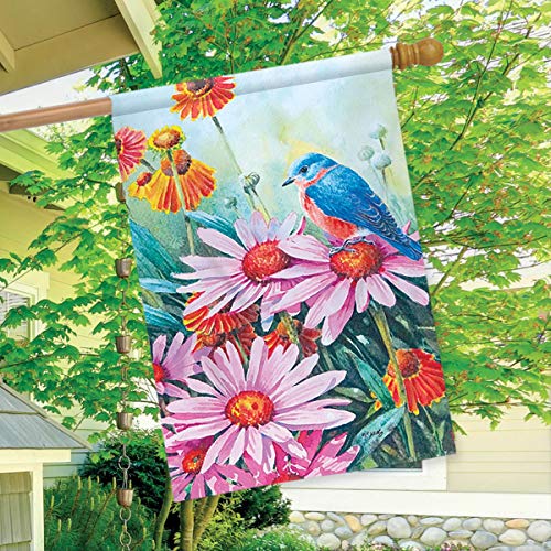 Bluebird and coneflowers flag hanging from a porch beside a leafy tree