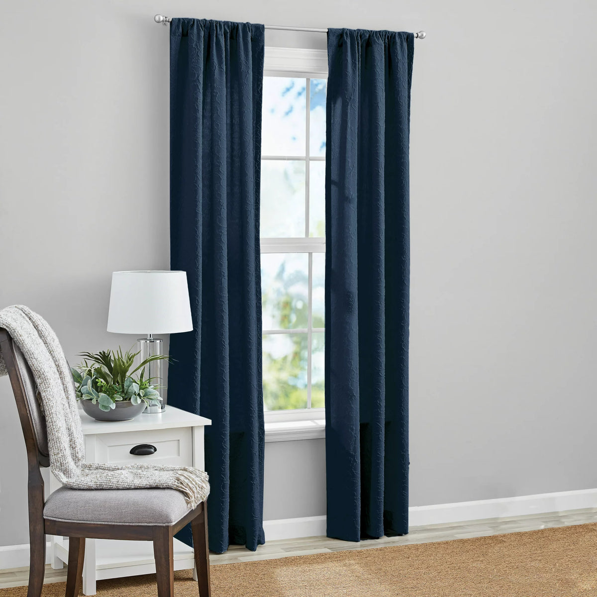 Two navy textured curtain panels on a silver rod framing a window