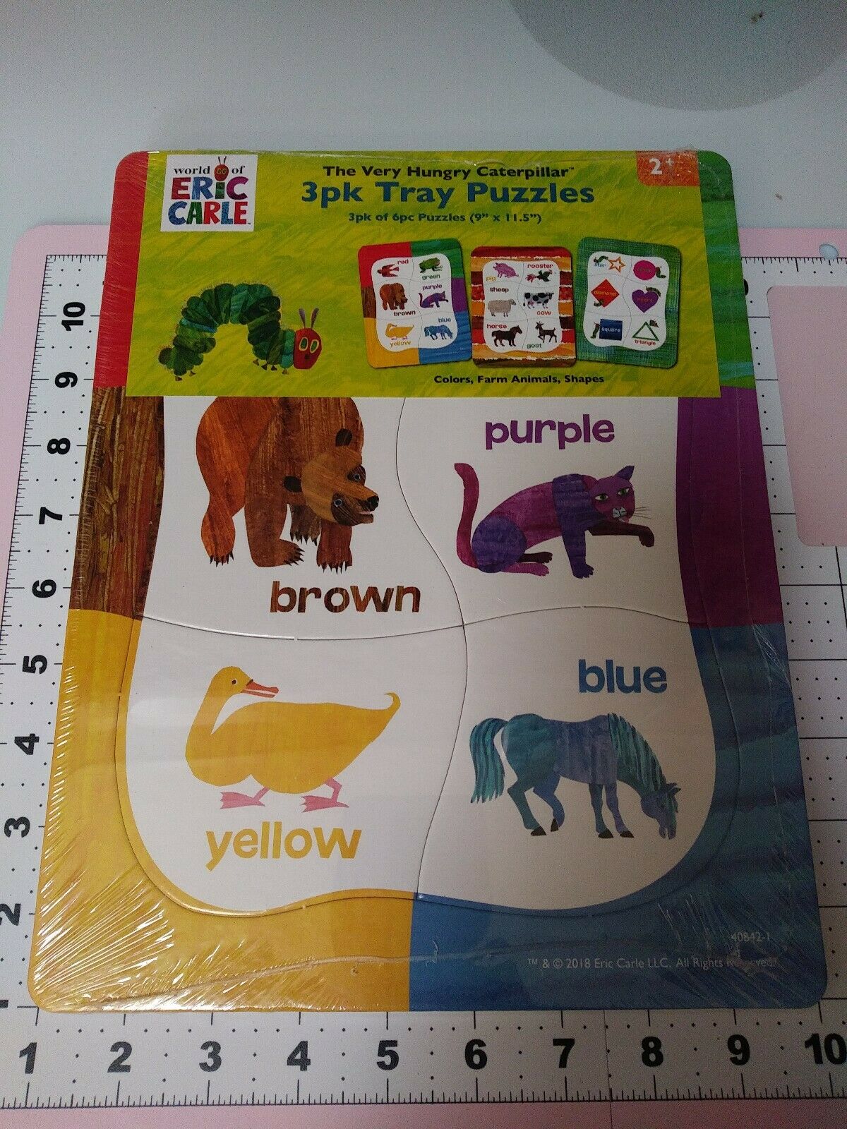 Shrink-wrapped pack of three caterpillar tray puzzles: colours, farm animals and shapes, on a ruler mat