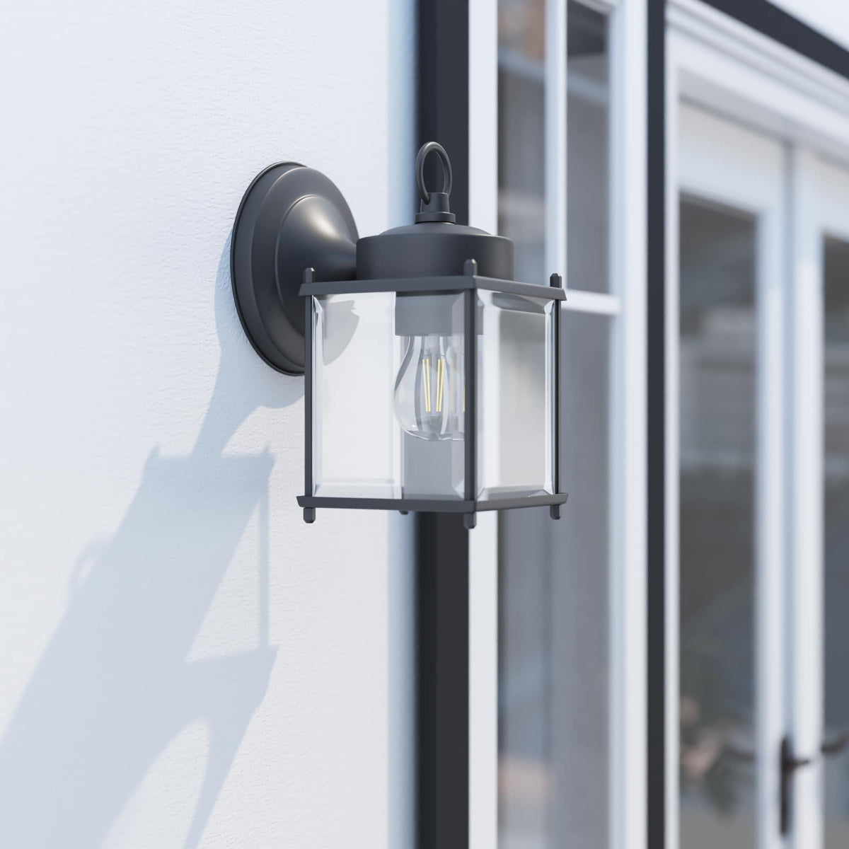 Black square lantern wall light with clear glass mounted beside a white door