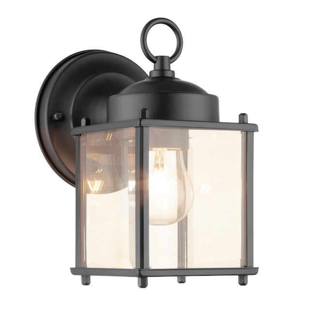 Black lantern wall light with a glowing clear bulb behind beveled glass