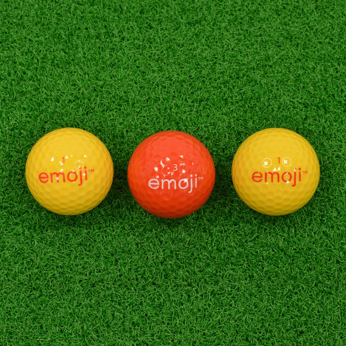 Back of the three golf balls showing the emoji brand name, yellow and red