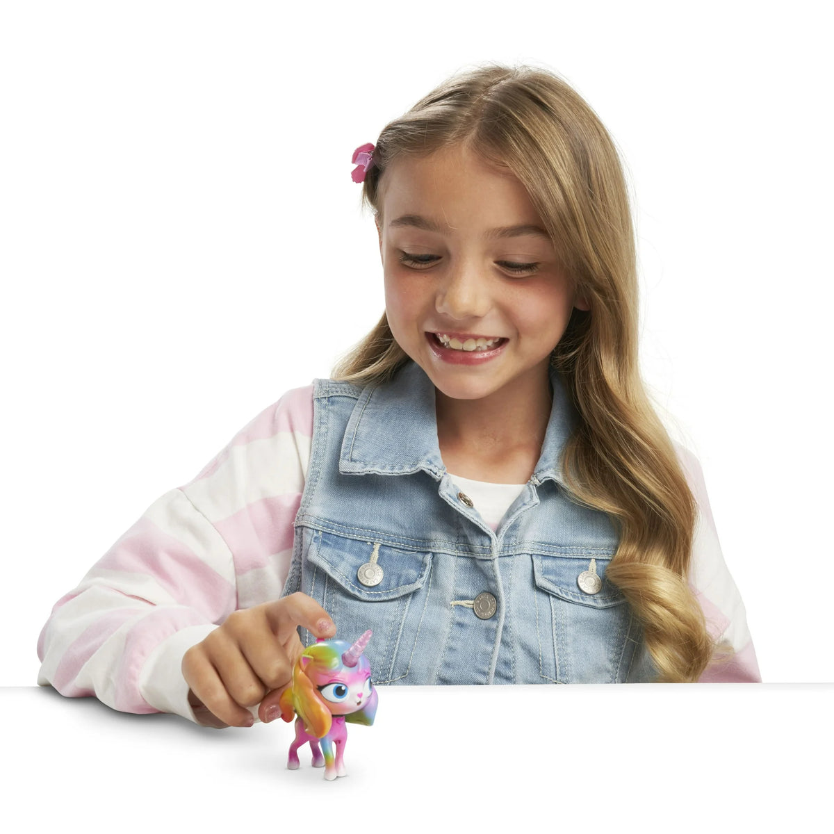 Smiling girl in a denim vest pressing the head of the rainbow unicorn kitty figure