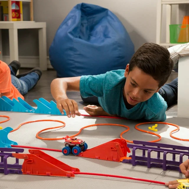Boy lying on the floor setting a red truck on the rope track by red ramps