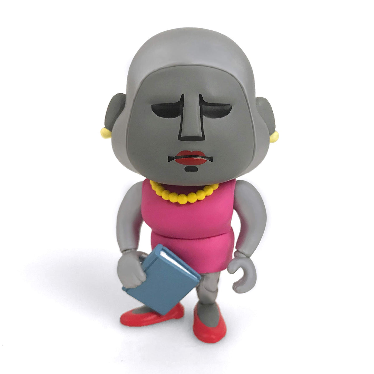 Grey-faced vinyl figure in a pink dress and yellow beads holding a blue book