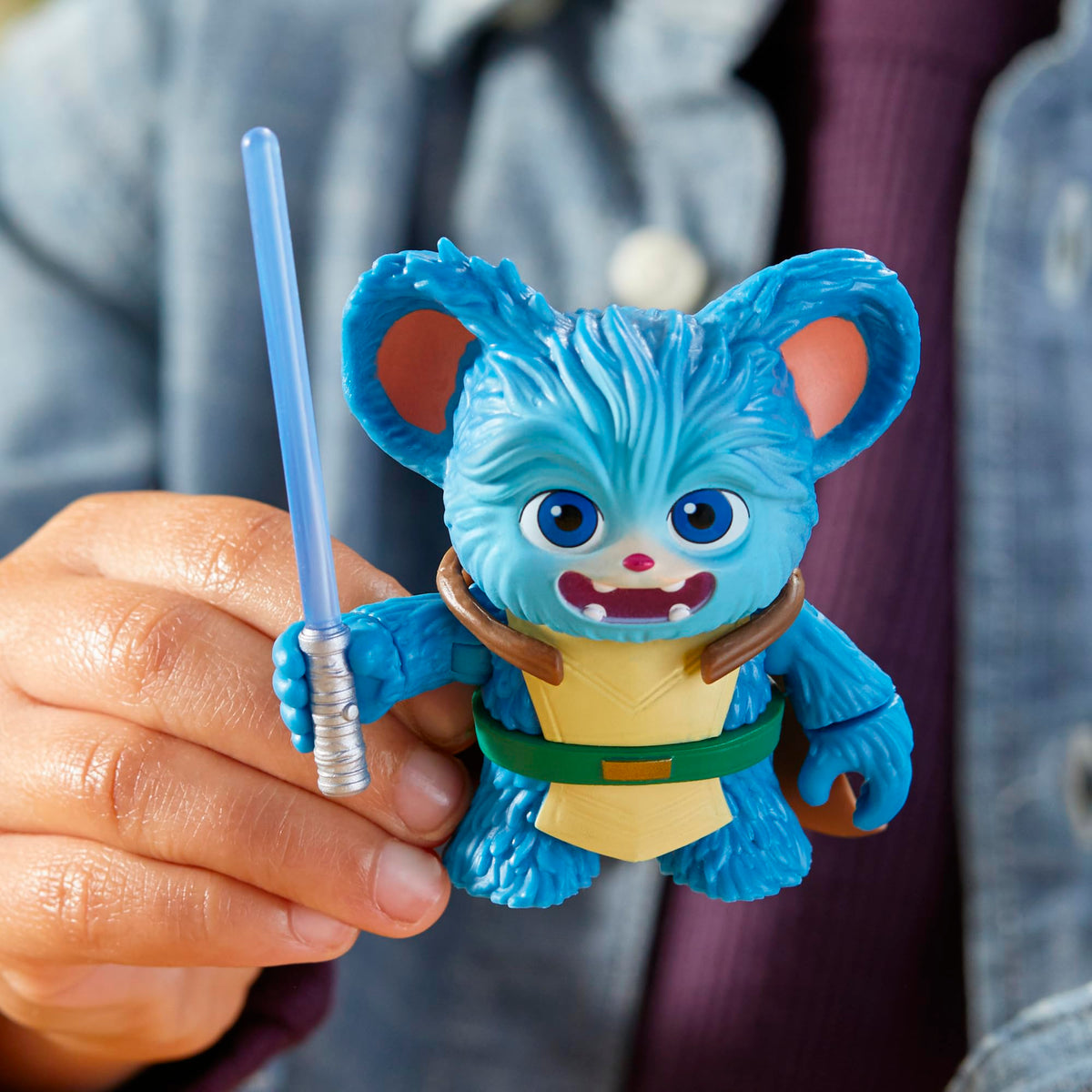 Hand holding the open-mouthed blue furry figure with its blue lightsaber