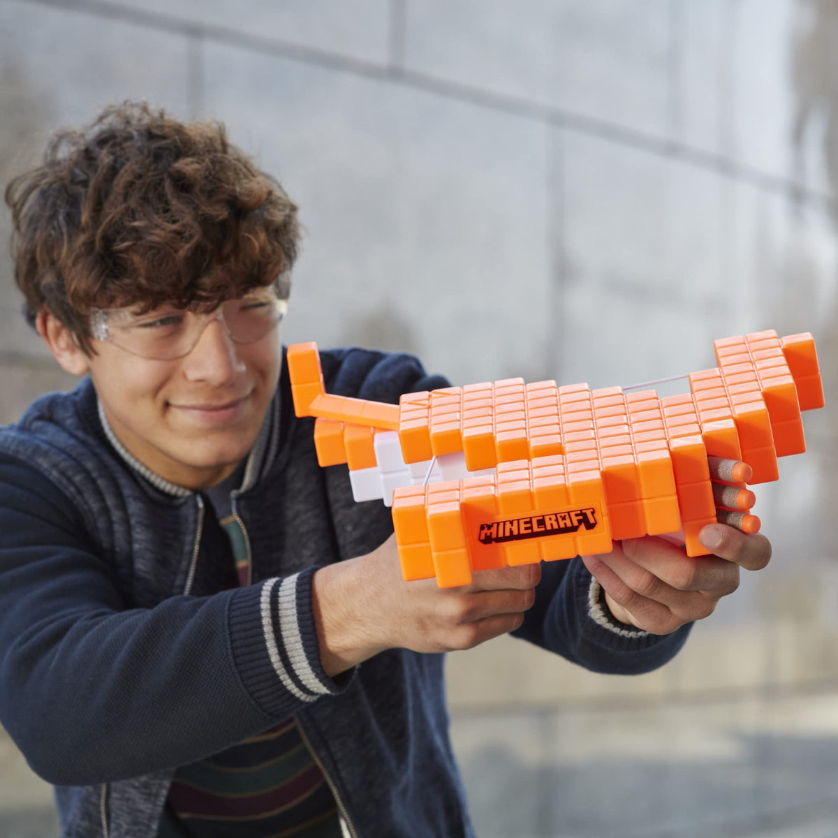 Smiling teen in safety glasses aiming the orange pixel crossbow