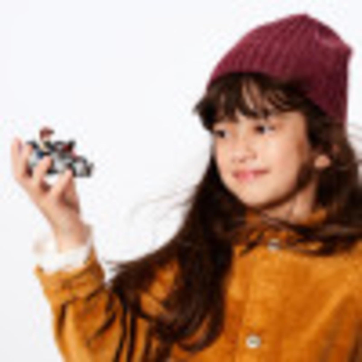 Girl in a burgundy beanie holding up the small Millennium Falcon build