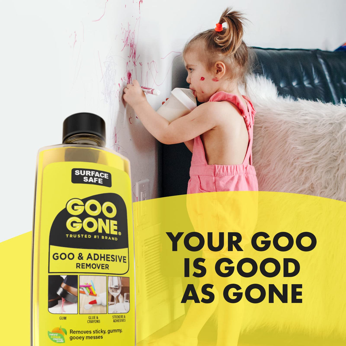 Toddler drawing on a white wall with a red marker next to the remover bottle