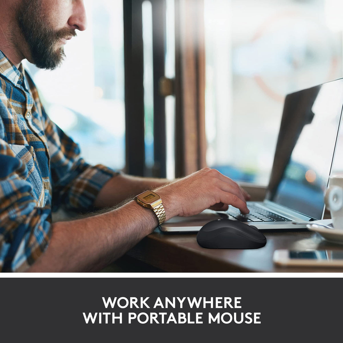 Man typing on a laptop in a cafe with the black wireless mouse on the table