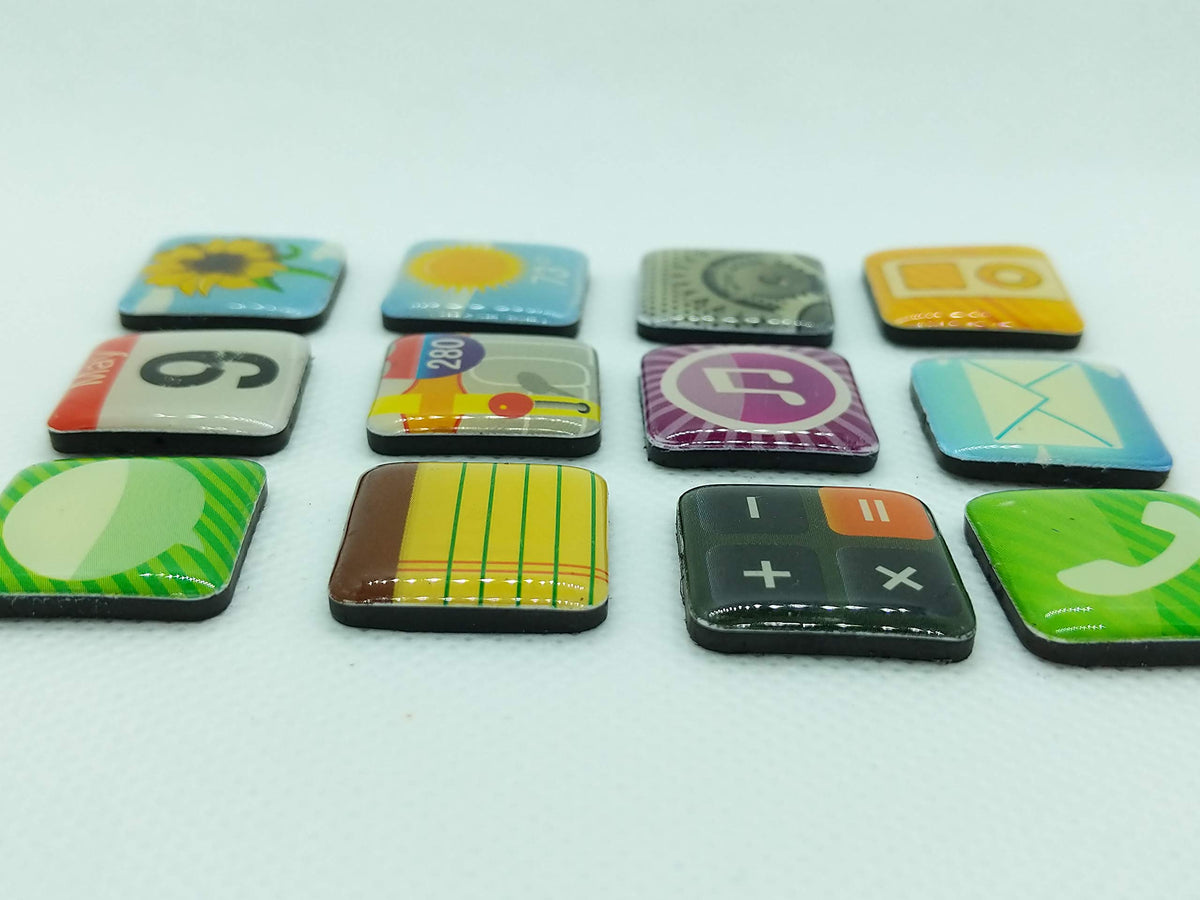 Low angle view of 12 domed app icon magnets on a white surface showing their black magnetic backs