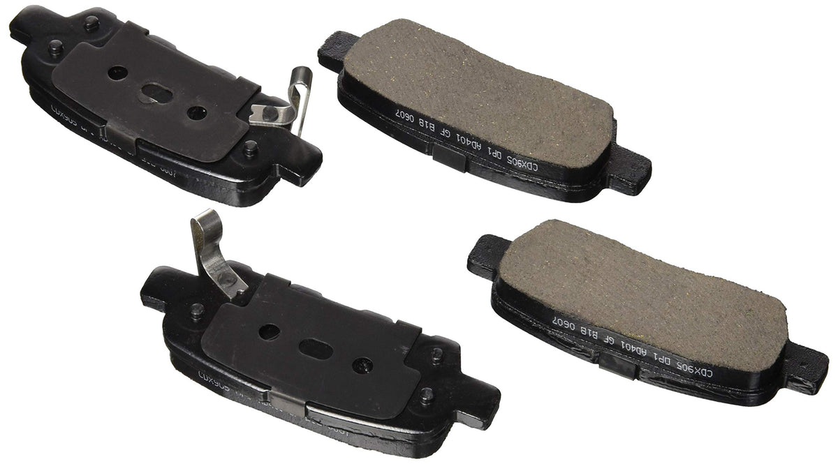 Four black ceramic rear brake pads, two showing friction surface and two backing plates