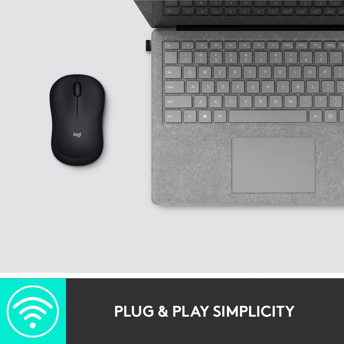 Black wireless mouse on a desk beside a grey laptop with a USB receiver plugged in