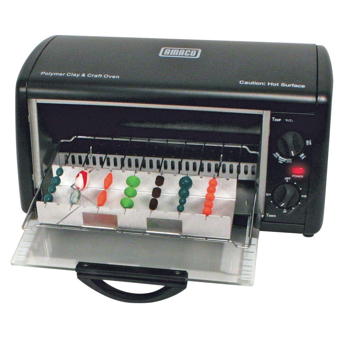 Black countertop craft oven with its glass door open and clay beads on skewers inside