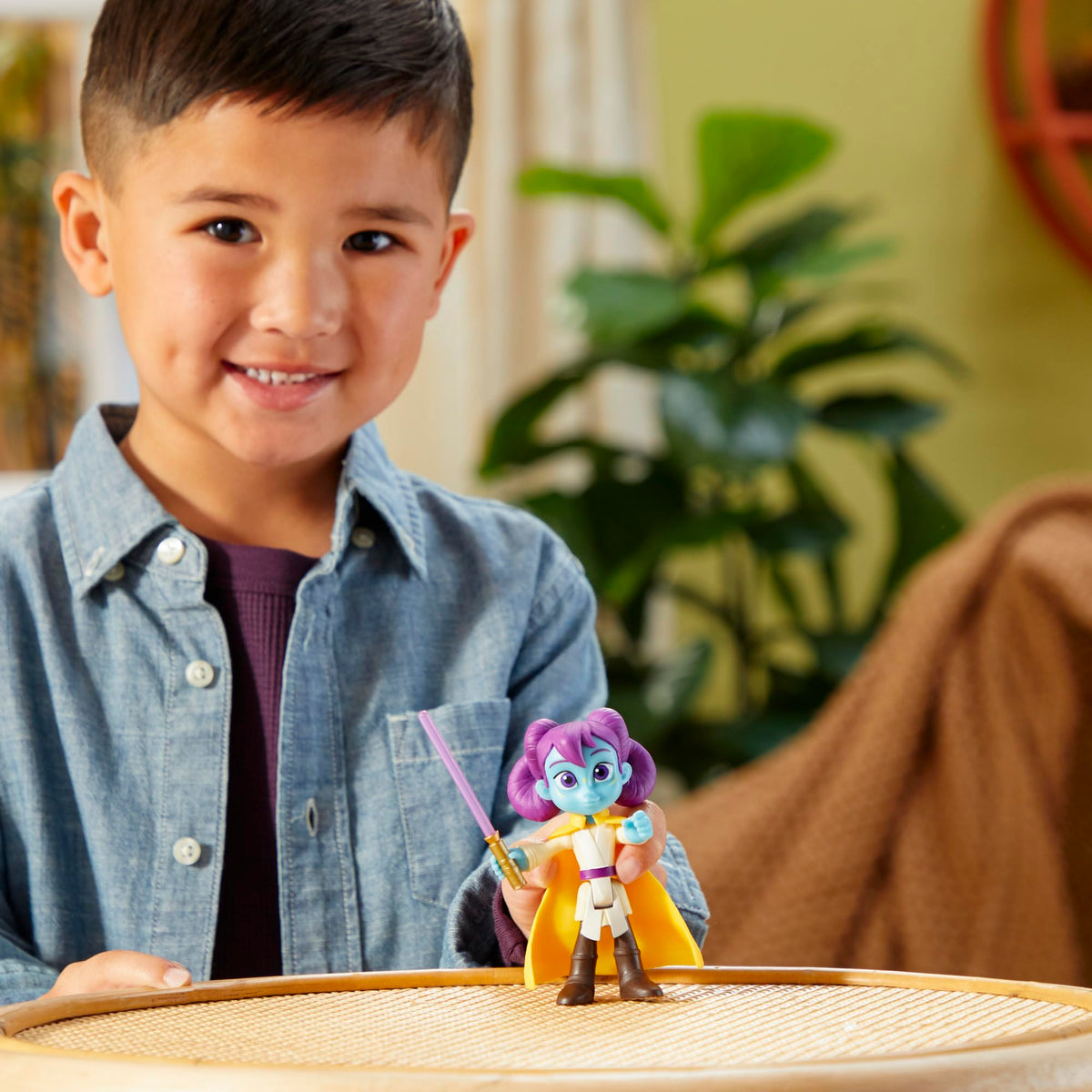 Smiling boy showing the yellow-caped figure on a rattan table