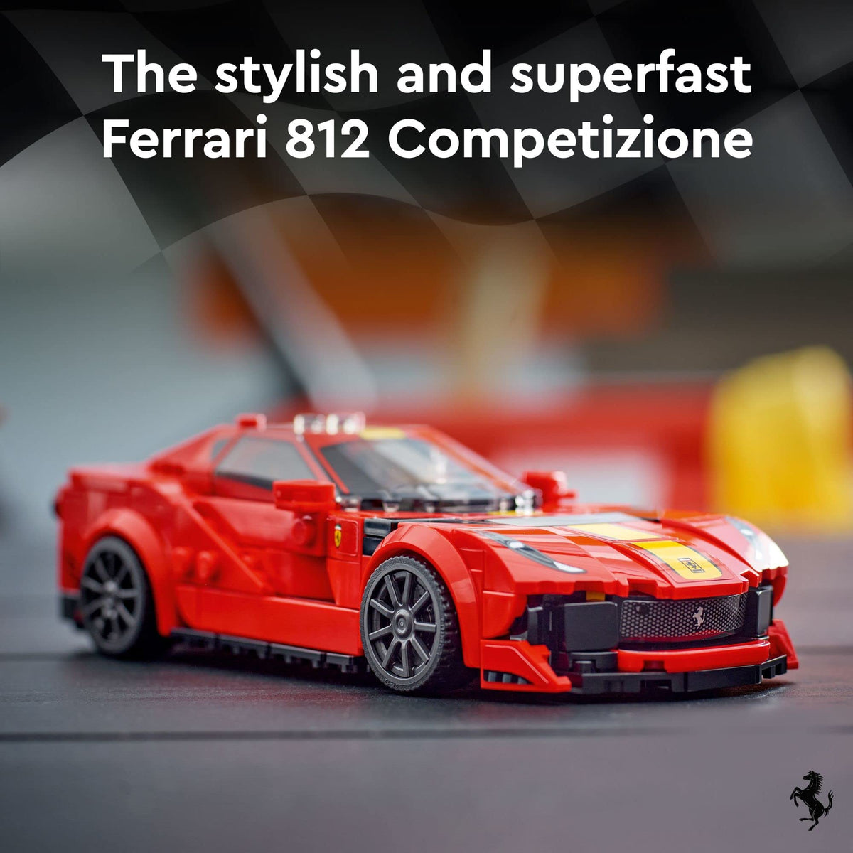 Front three-quarter view of the red brick supercar with yellow bonnet stripes and black grille