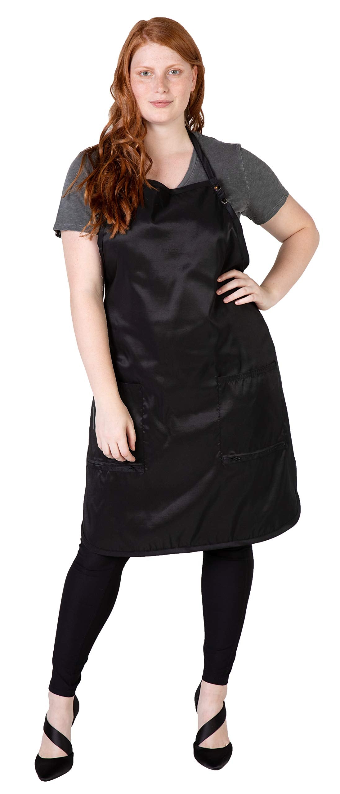 Red-haired woman wearing a long black stylist apron with two zippered bottom pockets