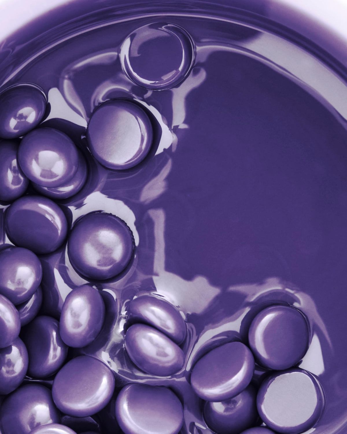 Close-up of purple wax beads melting into smooth liquid wax in the cup