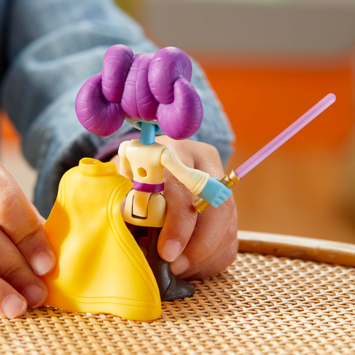 Back view of the figure with the removable yellow cape being taken off